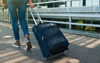 Person rolling a suitcase on a sidewalk - Holder's Pest Solutions in Houston tX